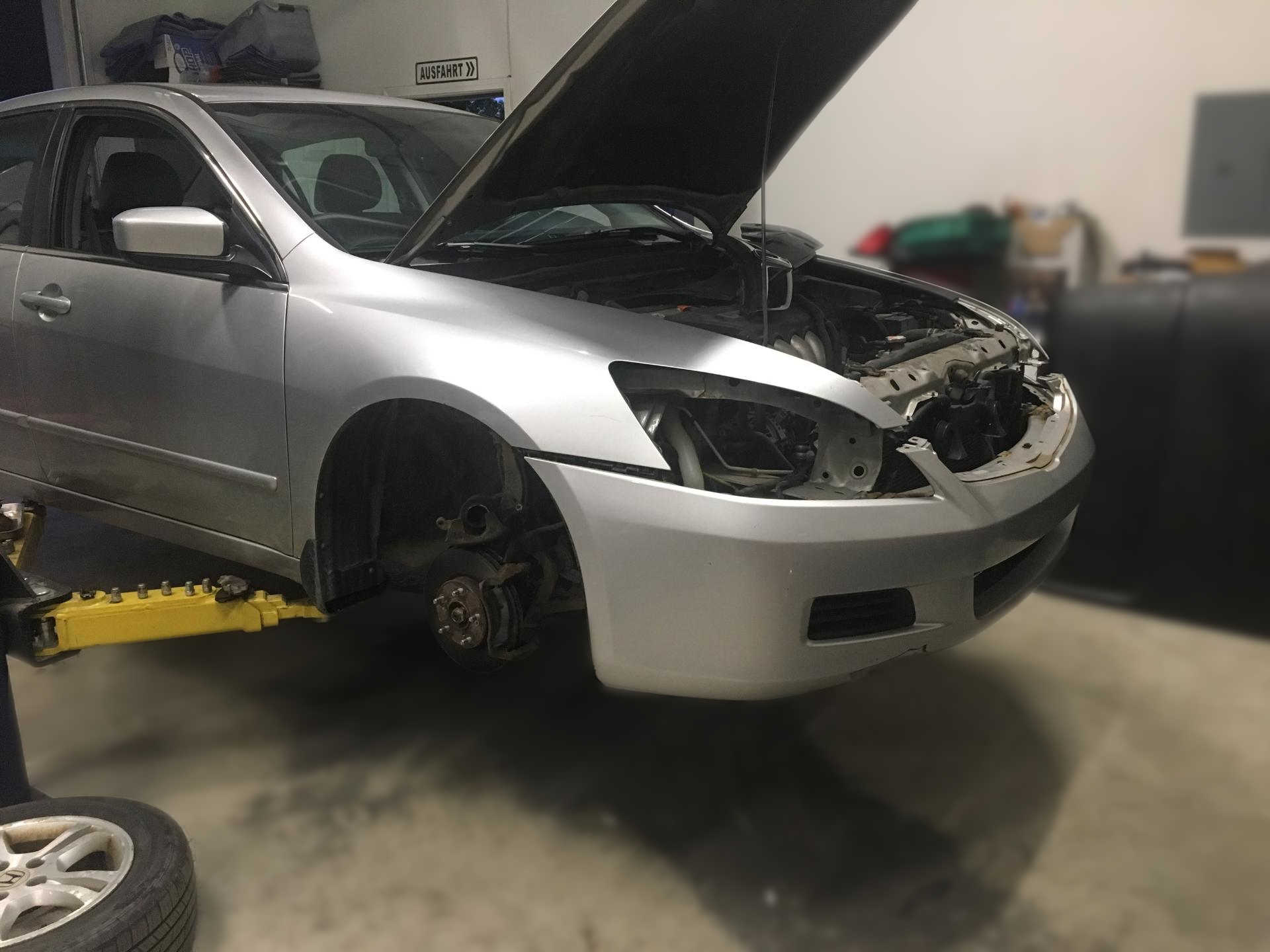 Honda sedan on a hydraulic lift with the front tire and headlights removed